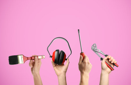 People holding different tools in hands against pink background, closeup.の写真素材