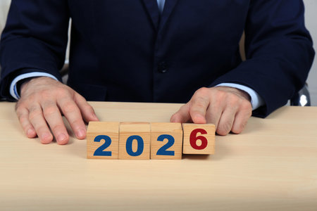 New 2026 Year. Businessman with cubes at wooden table, closeup. Startup, goals, plans