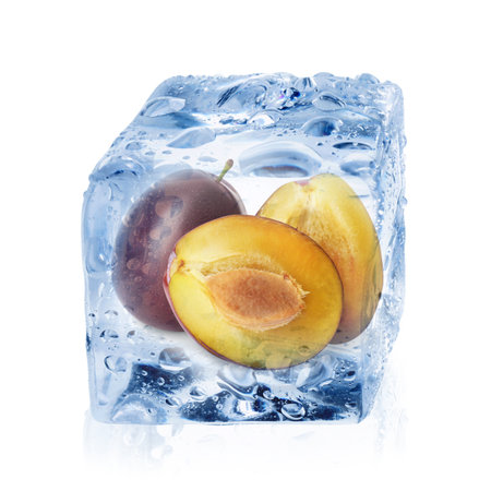 Fresh plums inside ice cube isolated on whiteの写真素材
