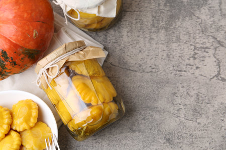 Pickled pattypan squashes and pumpkin on gray textured table, flat lay. Space for textの写真素材