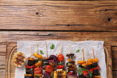 Skewers with tasty grilled vegetables served on wooden table, top view. Space for textの写真素材