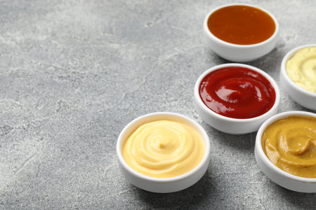Different tasty sauces in bowls on gray table, closeup. Space for textの写真素材