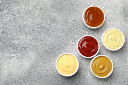 Different tasty sauces in bowls on gray table, flat lay. Space for textの写真素材