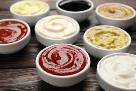 Different sauces in bowls on wooden table, closeupの写真素材