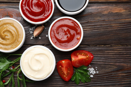 Different sauces, spices and herbs on wooden table, flat lay. Space for textの写真素材