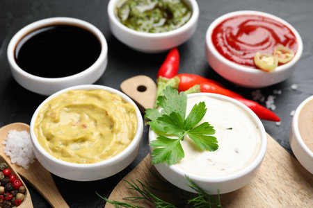 Different sauces, spices and herbs on black table, closeupの写真素材