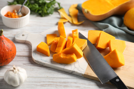 Cut pumpkin, knife, spices and seeds on light wooden table, closeupの写真素材
