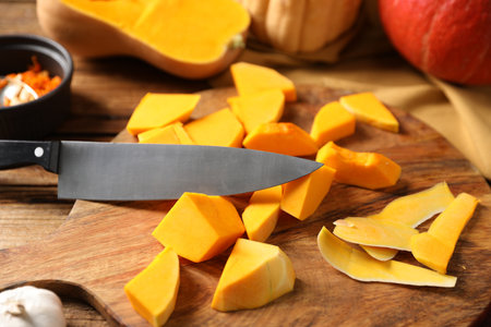 Cut pumpkin, knife, garlic and seeds on wooden table, closeupの写真素材