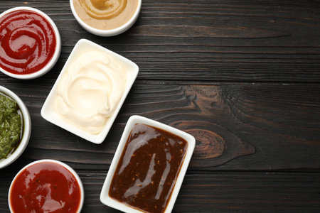 Different sauces in bowls on wooden table, flat lay. Space for textの写真素材