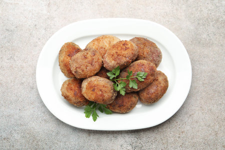 Tasty meat patties with parsley on gray table, top view