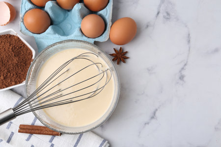 Liquid dough in bowl, ingredients on white table, flat lay. Space for textの写真素材