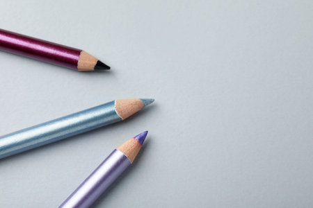 Colorful eye pencils on light background, above view. Space for text