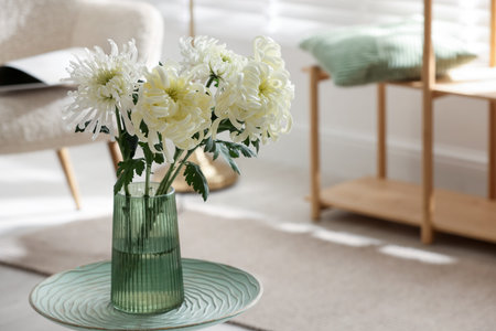 Beautiful white chrysanthemum flowers in vase on coffee table indoors, space for textの写真素材