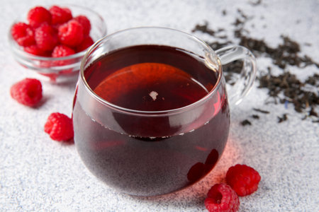 Delicious tea, raspberries and brew served on light table, closeupの写真素材