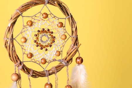 Beautiful dream catcher on yellow background, closeup. Space for textの写真素材
