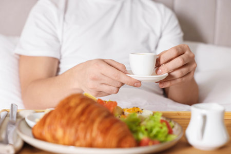 Man having breakfast in bed, closeup.
