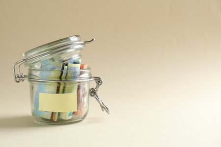 Saving money. Jar with banknotes on beige background, space for textの写真素材
