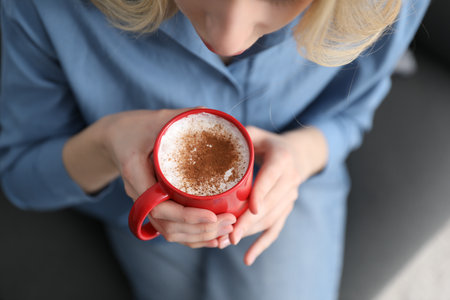 Woman having tasty cocoa drink with cinnamon at home, above viewの写真素材