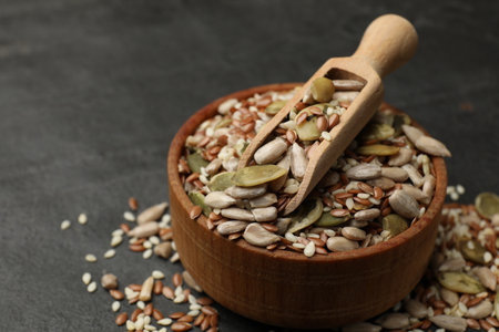 Mix of seeds and scoop in bowl on black textured table, closeupの写真素材