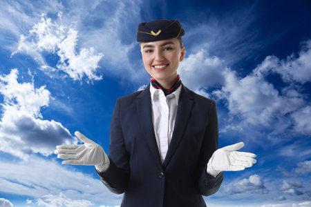 Happy stewardess in uniform against blue sky with clouds