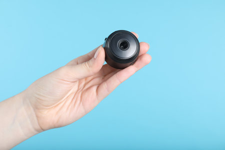 Woman with hidden camera on light blue background, closeupの写真素材