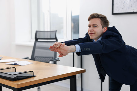 Young businessman doing stretching exercise in office