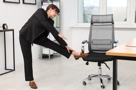 Young businesswoman doing stretching exercise in officeの写真素材