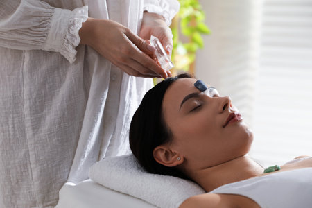 Woman undergoing crystal therapy to heal or restore her aura indoorsの写真素材