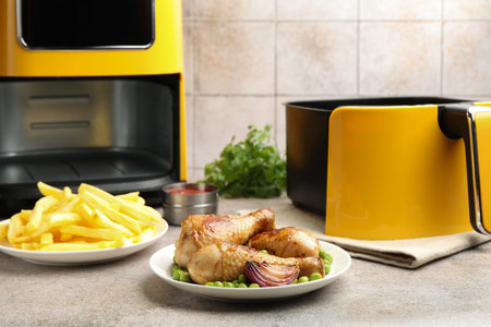 Grilled chicken drumsticks and French fries on gray table, closeupの写真素材