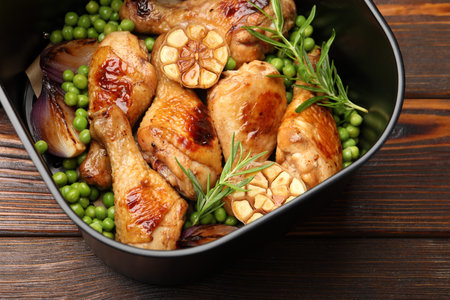 Air fryer basket with grilled chicken drumsticks, spices and green peas on wooden table, top viewの写真素材