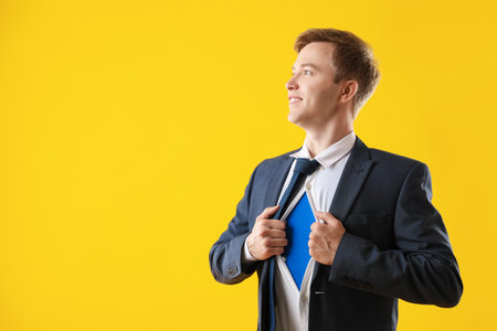 Businessman wearing superhero costume under his clothes on yellow background. Space for textの写真素材