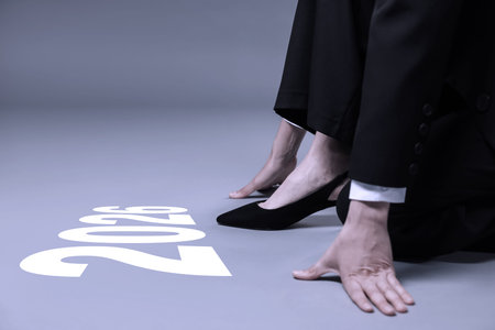 New Year. Businesswoman in starting position in front of numbers 2026 on floor, closeup