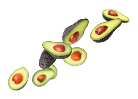 Fresh avocado falling on white background. Whole and sliced