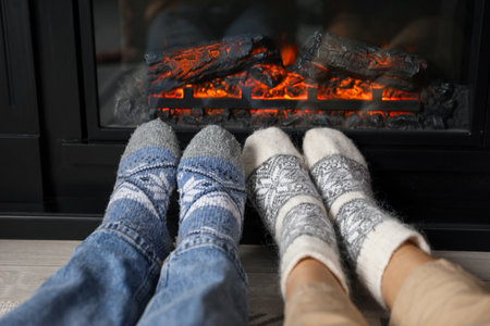 Couple in warm socks resting near fireplace at home, closeupの写真素材