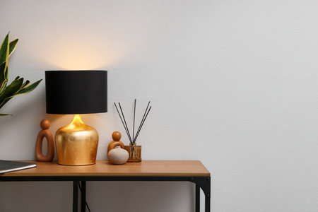 Stylish lamp and decor on wooden table near white wall indoors, space for textの写真素材