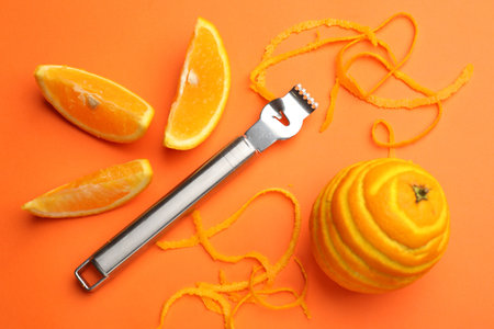 Orange zest, fresh fruits and zester tool on color background, flat lay