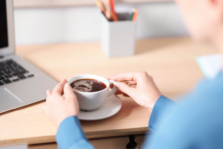 Woman having coffee break at wooden table indoors, closeupの写真素材