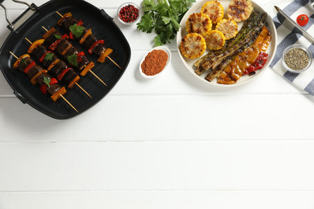 Skewers with tasty grilled vegetables served on white wooden table, flat lay. Space for textの写真素材