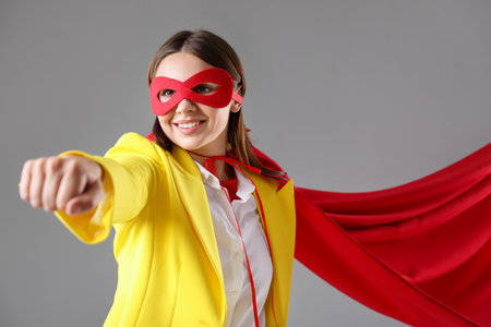 Businesswoman wearing superhero costume on gray backgroundの写真素材