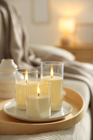 Beautiful candles on sofa indoors, closeup. Space for textの写真素材