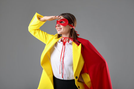 Businesswoman wearing superhero costume on gray backgroundの写真素材