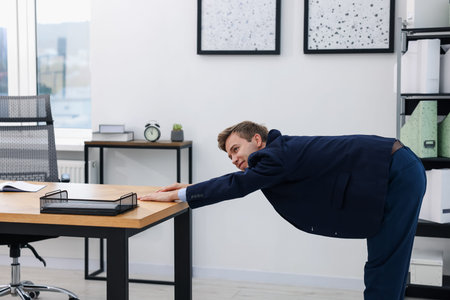 Young businessman doing stretching exercise in office