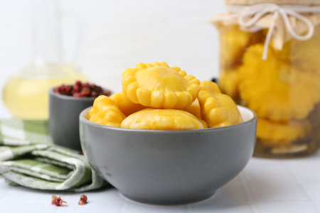 Pickled pattypan squashes in bowl on white tiled table, closeupの写真素材