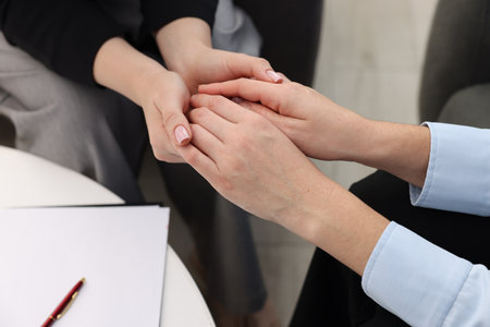 Psychologist supporting woman during therapy session indoors, closeupの写真素材