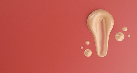 Samples of foundation on red background, flat lay. Space for textの写真素材