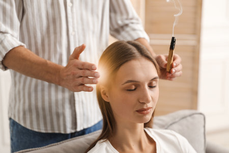 Reiki master with Palo Santo stick healing patient's aura during therapy indoors, closeupの写真素材