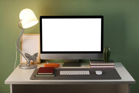 Stylish workplace with computer and gray mat on desk in office