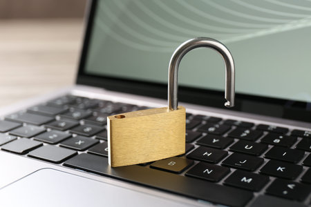 Password concept. Open padlock and laptop on table, closeup