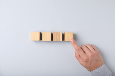 Man with wooden cubes on light background, top viewの写真素材
