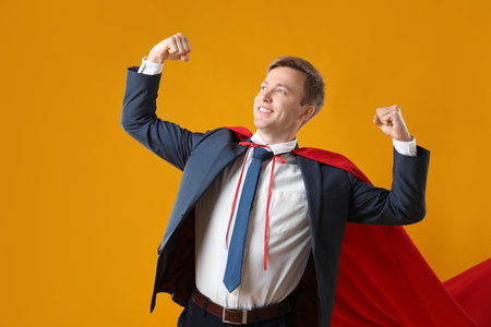 Businessman wearing superhero cape on yellow backgroundの写真素材